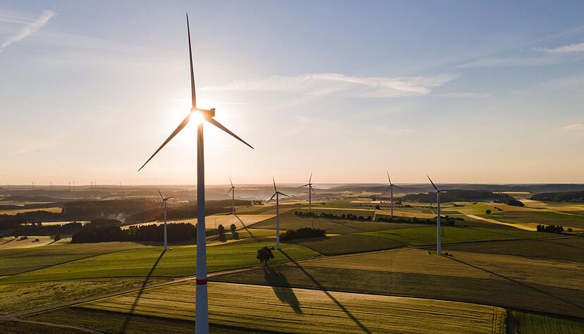Windräder stehen während des Sonnenaufgangs auf einem Feld. Windräder stehen während des Sonnenaufgangs auf einem Feld.