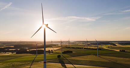 Windräder stehen während des Sonnenaufgangs auf einem Feld.