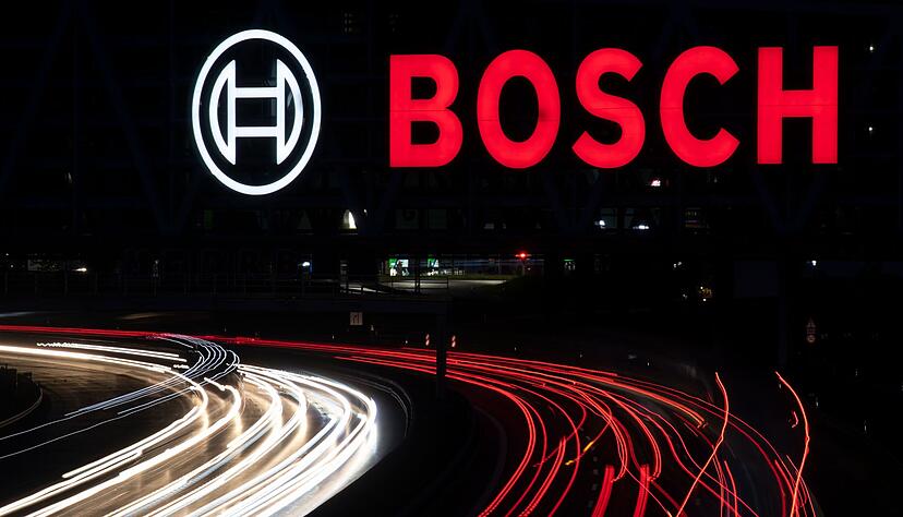 Das Logo des Technologiekonzerns Bosch leuchtet auf einem Parkhaus der Messe Stuttgart über der A8.