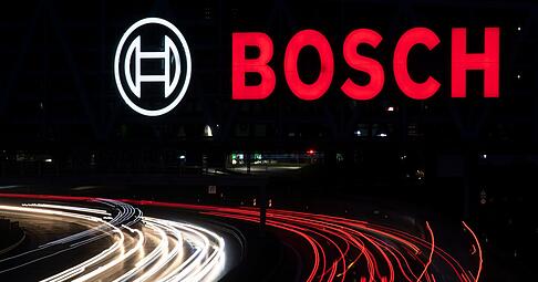 Das Logo des Technologiekonzerns Bosch leuchtet auf einem Parkhaus der Messe Stuttgart über der A8.