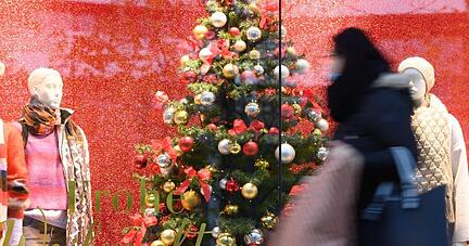 Eine Passantin geht mit einer Papiertüte auf einer Einkaufsstraßeentlang. (Archivbild).