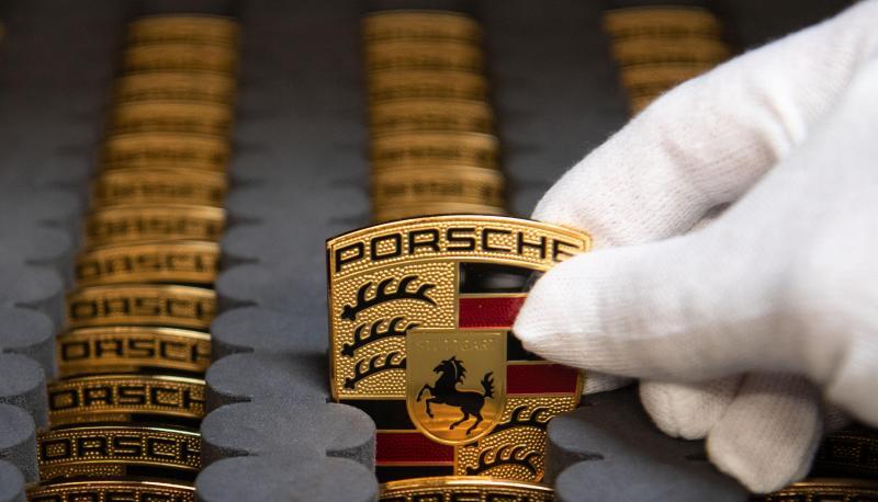 Ein Mitarbeiter der Porsche AG zeigt in der Produktion Porsche-Wappen. Foto: dpa