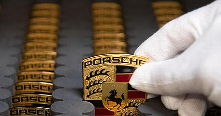 Ein Mitarbeiter der Porsche AG zeigt in der Produktion Porsche-Wappen.