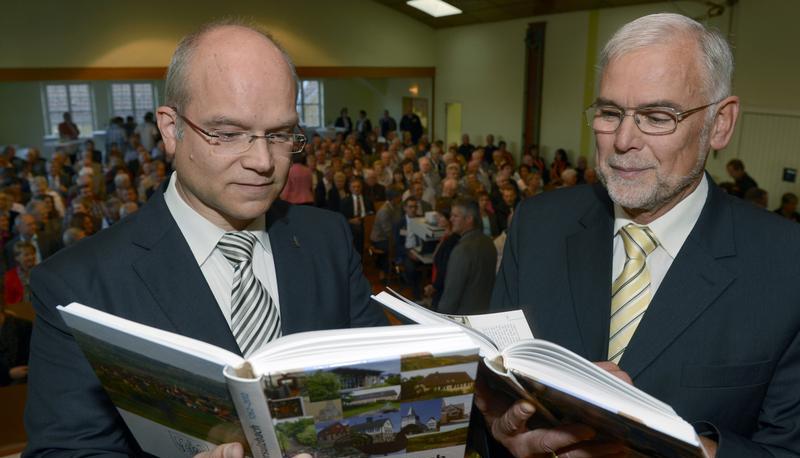 Initiator Werner Uhlmann (rechts) &uuml;bergibt die ersten druckfrischen Exemplare des Ortsbuchs in der Kelter-Halle an B&uuml;rgermeister Norbert Heuser.
Foto: Mario Berger