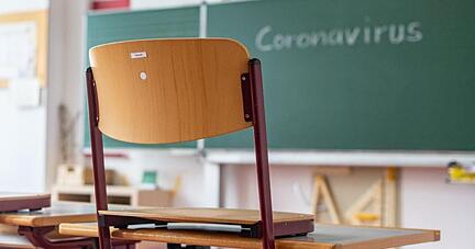 «Coronavirus» steht auf einer Tafel in einem leeren Klassenzimmer.