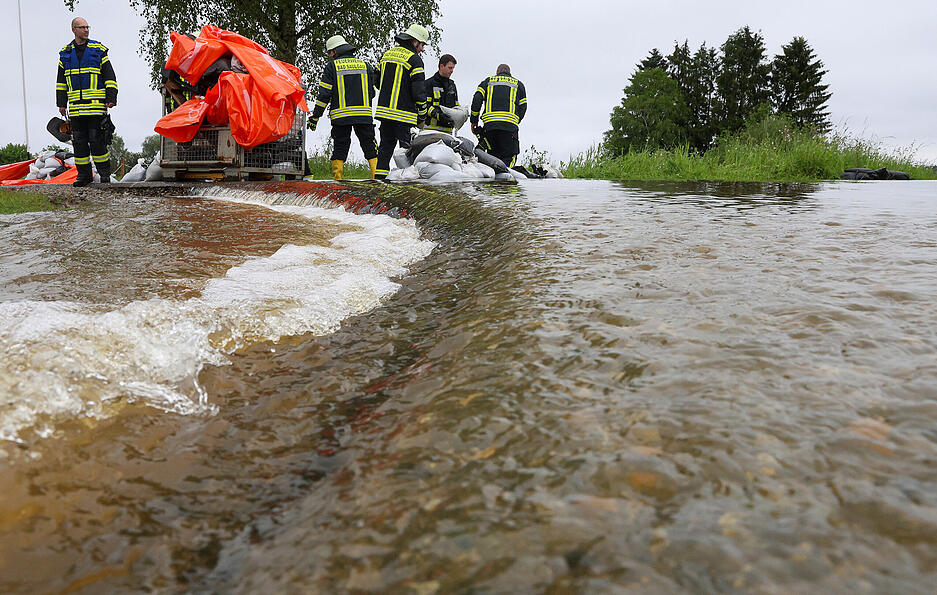 Einsatzkräfte der Feuerwehr errichten am Nonnenbach im Ortsteil Moosheim einen Damm mit Sandsäcken gegen das Hochwasser.
