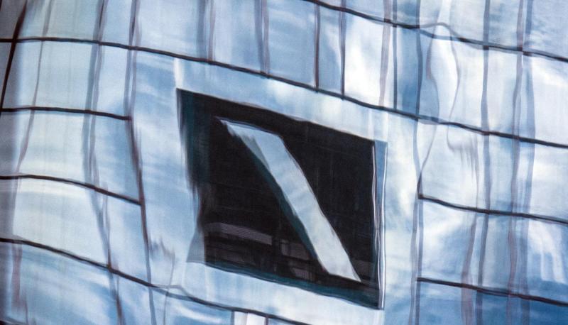 Die Zentrale der Deutschen Bank spiegelt sich in einer Glasfassade in Frankfurt am Main.
