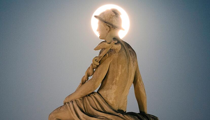 Hinter dem Kopf einer Statue des Gottes Merkur steht in Kopenhagen ein Vollmond am Himmel. Hinter dem Kopf einer Statue des Gottes Merkur steht in Kopenhagen ein Vollmond am Himmel.