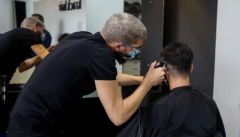 Ein Friseur schneidet die Haare eines Kunden in einem Friseursalon.