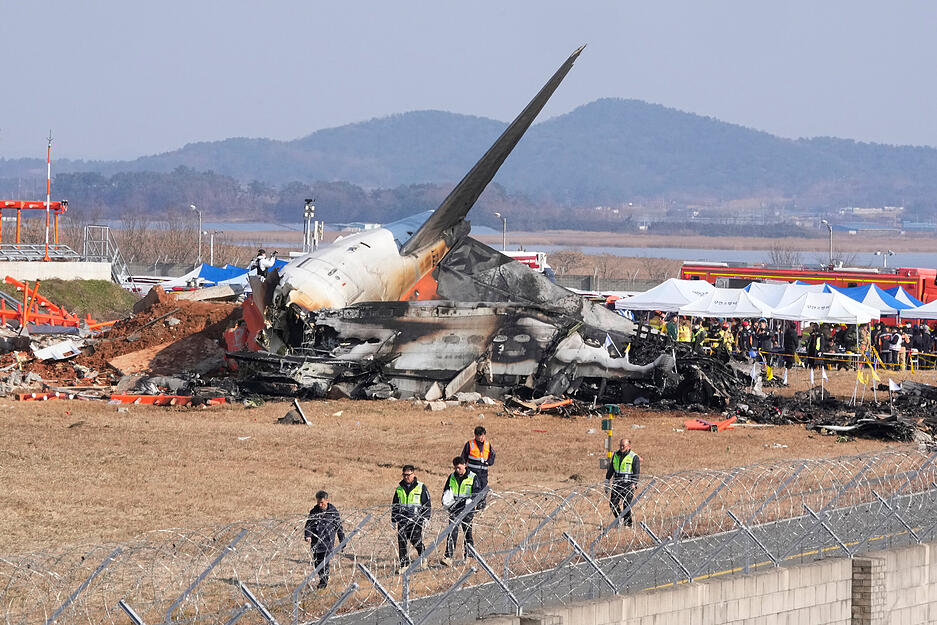 Feuerwehrleute und Rettungskr&auml;fte arbeiten an dem Wrack eines Flugzeugs auf dem internationalen Flughafen von Muan. Bei der Landung am internationalen Flughafen von Muan in S&uuml;dkorea ist ein Passagierflugzeug verungl&uuml;ckt.