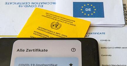 Ein Impfpass und ein Smartphone liegen auf einem Impfzertifikat.