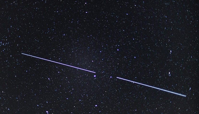 Am Nachthimmel sind Starlink-Satelliten als leuchtende Spur zu erkennen.