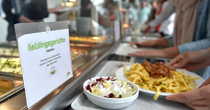 Mitarbeiter holen sich in einer Kantine ihr Mittagessen.