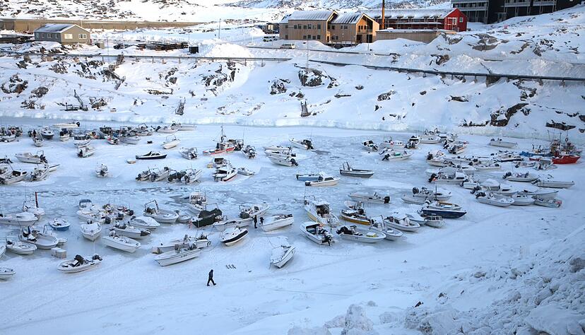 Ein Mann geht im Hafen &uuml;ber das zugefrorene Wasser.