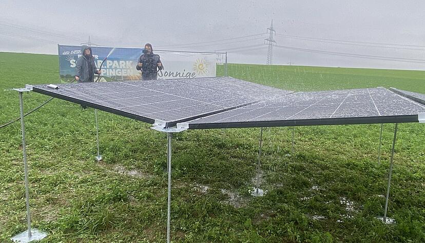 Sarah von Keudell hält mit dem Wasserschlauch auf die PV-Module und simuliert damit einen starken Regenguss. Das Wasser fließt über die Zwischenräume ab.