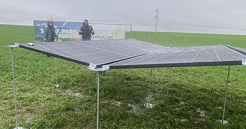 Sarah von Keudell hält mit dem Wasserschlauch auf die PV-Module und simuliert damit einen starken Regenguss. Das Wasser fließt über die Zwischenräume ab.