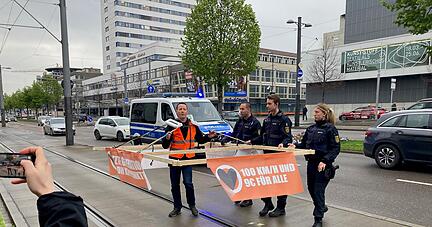 Vor dem Gerichtsprozess in Heilbronn gegen Klimaaktivisten der "Letzten Generation" ist ein Aktivist mit einem Holzkonstrukt auf der Allee unterwegs.