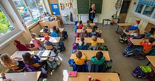 Schüler einer ersten Grundschulklasse sitzen im Unterricht auf ihren Plätzen.