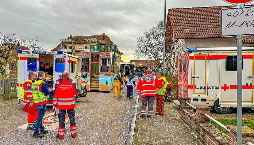 Rettungswagen, Karnevalisten und Einsatzkräfte stehen in der Nähe der Unfallstelle.
