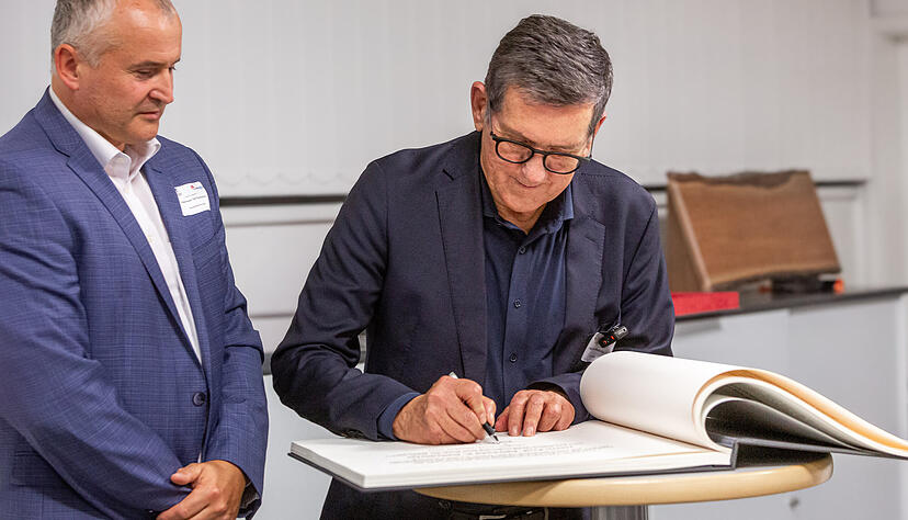 Geilsd&ouml;rfer unterschreibt seinen Eintrag im Goldenen Buch der Stadt Leingarten. B&uuml;rgermeister Ralf Steinbrenner schaut zu.
