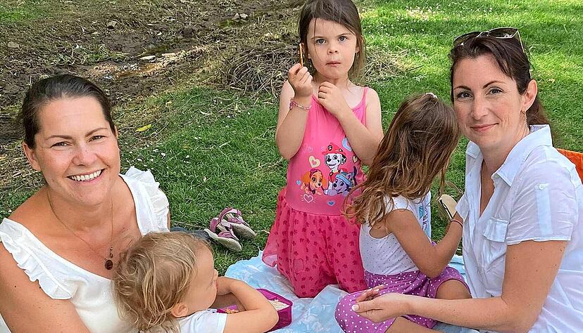 Natalie und Caro sitzen mit Amelie, Emilia und Rosalie im Schatten unter hohen Bäumen im Hofgarten und machen Picknick. Natalie und Caro sitzen mit Amelie, Emilia und Rosalie im Schatten unter hohen Bäumen im Hofgarten und machen Picknick.