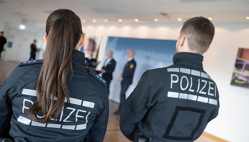 Zwei Polizeibeamten, die neue Uniformen anhaben, verfolgen eine Pressekonferenz.