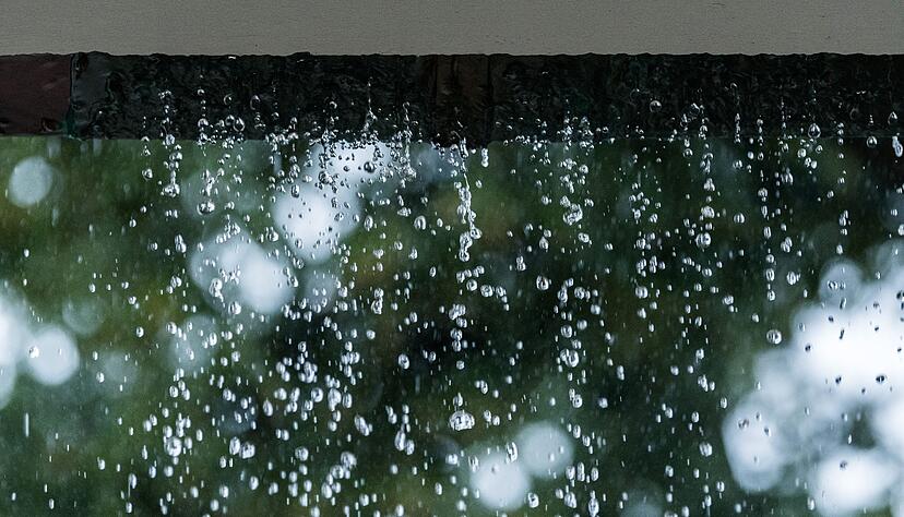 Statt zum Abfluss schießt das Regenwasser während eines Unwetters an einer verstopften Regenrinne hinunter und sucht sich seinen Weg. Statt zum Abfluss schießt das Regenwasser während eines Unwetters an einer verstopften Regenrinne hinunter und sucht sich seinen Weg.