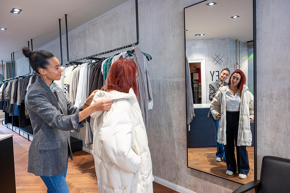 Verkäuferin Melissa Domingos mit Christina Knapp, die in der Boutique Rey einen Mantel anprobiert.