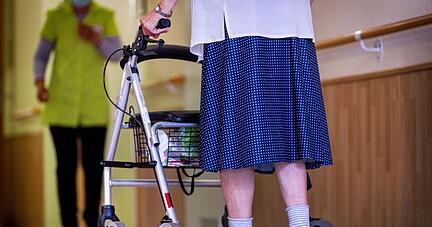 Eine ältere Dame geht mit ihrem Rollator über einen Flur. Eine ältere Dame geht mit ihrem Rollator über einen Flur.