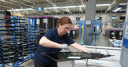 Eine Mitarbeiterin von Fuyao "trimmt" Autoscheiben und sortiert sie für die weitere Verarbeitung. Zahlreiche Stellen in der Produktion fallen weg.
Foto: Christian Gleichauf