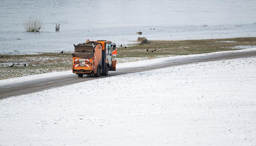 Ein Winterdienst-Fahrzeug fährt auf dem Radweg an den verschneiten Elbwiesen in Dresden entlang. Ein Winterdienst-Fahrzeug fährt auf dem Radweg an den verschneiten Elbwiesen in Dresden entlang.