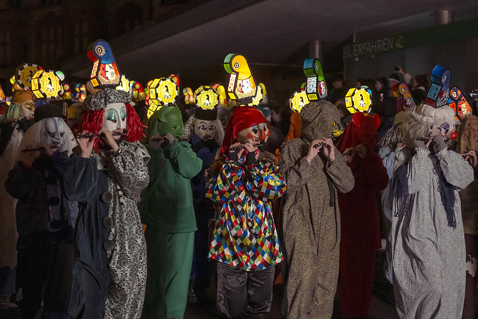 Fasnachtscliquen ziehen am Morgestraich mit Laternen durch die Stra&szlig;en in Basel.