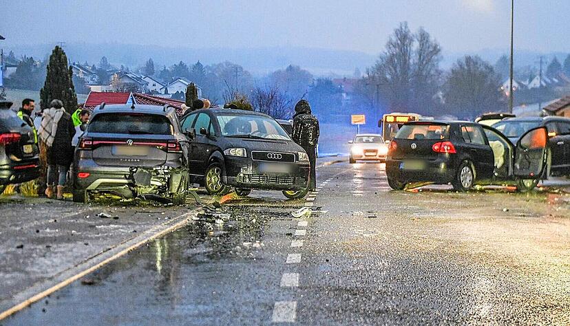 Nach einem Unfall bei Glatteis mit mehreren Fahrzeugen in Aalen stehen Helfer und Beteiligte an den Autos auf einer Straße.