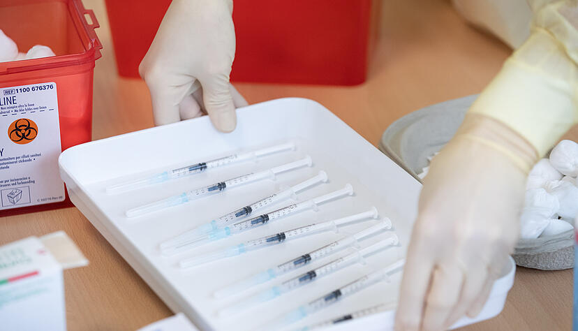 Eine Krankenschwester stellt ein Tablett mit Spritzen, die einen Impfstoff gegen das Coronavirus enthalten, auf einen Tisch. Foto: dpa