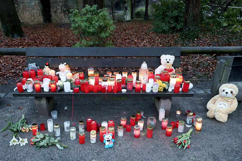 Trauerkerzen, Blumen und Kuscheltiere liegen nach dem tödlichen Angriff in einem Park am Tatort auf einer Bank. In einem Park in Aschaffenburg waren am Vortag ein zweijähriger Junge und ein 41-jähriger Mann getötet sowie zwei weitere Menschen schwer verletzt worden.