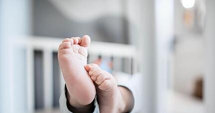 Die F&uuml;&szlig;e eines Babys sind in einem Kinderbett zu sehen.