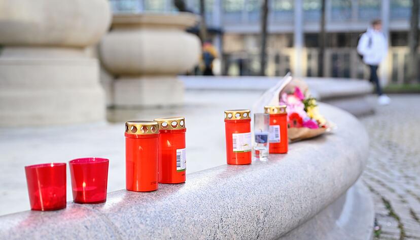 Menschen stellen Kerzen am Tatort in Mannheim auf und legen Blumen nieder.