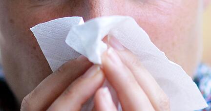 Eine Frau putzt sich die Nase.