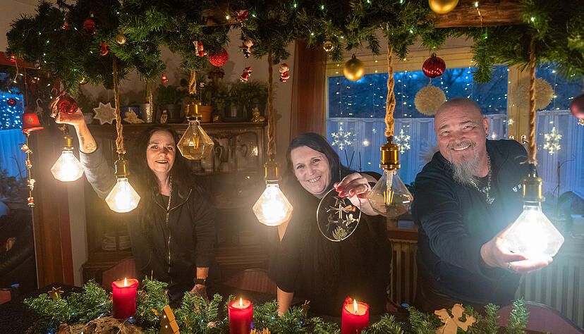 Grisu Neubeck (links) und Andy Neubeck mit Julia S. am geschm&uuml;ckten Esstisch der M&uuml;hle der Hoffnung. Julia S. freut sich, dass ihre Tochter zu Besuch kommt.