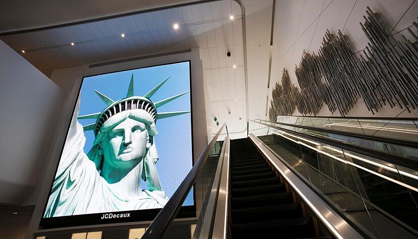 Ein Bildschirmbild der Freiheitsstatue begrüßt ankommende Reisende auf einer Rolltreppe im neuen Terminal B des Flughafens LaGuardia.  Offenbar sind nicht mehr alle Touristen willkommen.