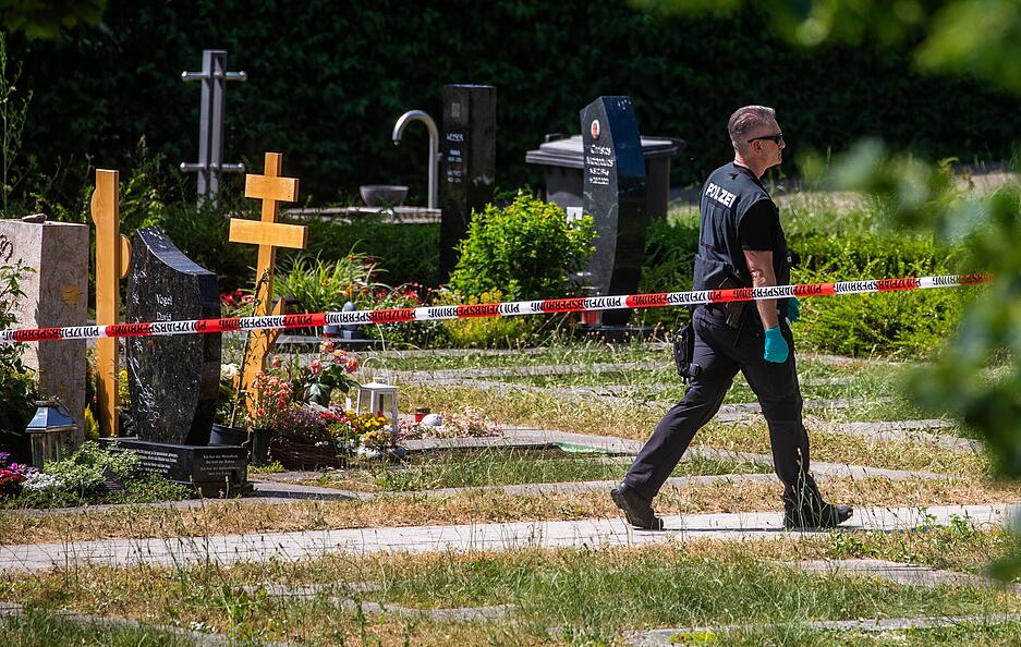 Ein Polizist läuft über den abgesperrten Teil an einem Tatort auf einem Friedhof. Durch den Wurf eines explodierenden Gegenstands auf eine Trauergemeinde gab es mehrere Verletzte. Ein Polizist läuft über den abgesperrten Teil an einem Tatort auf einem Friedhof. Durch den Wurf eines explodierenden Gegenstands auf eine Trauergemeinde gab es mehrere Verletzte.