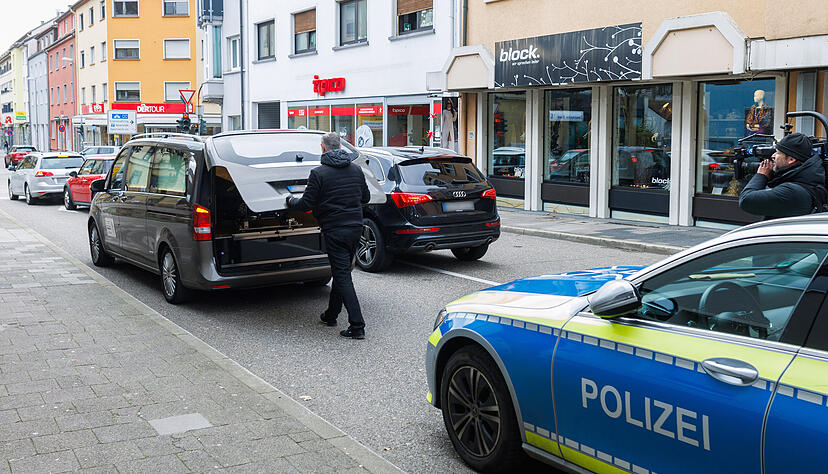 Ein Leichenwagen steht in Bruchsal auf der Straße vor einem Polizeiauto.