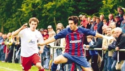 Die ausgestreckte Zunge deutet auf Konzentration und Eifer hin. Der Hollenbacher Christoph Schenk (rechts) versucht, sich im Zweikampf gegen seinen Wangener Gegenspieler zu behaupten. Die Zuschauer gucken interessiert zu.Foto: Kurt Gesper
