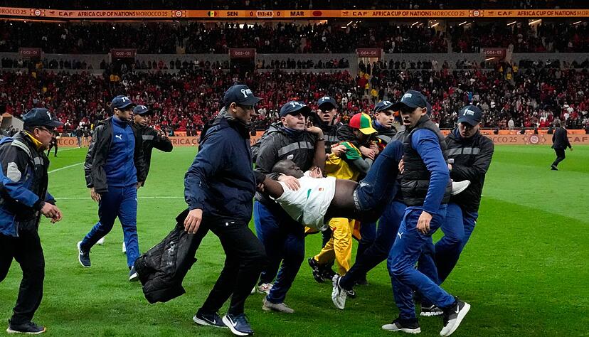 Ein auf das Spielfeld gest&uuml;rmter Anh&auml;nger des Senegal wird von Sicherheitskr&auml;ften vom Platz getragen. (Archivbild)