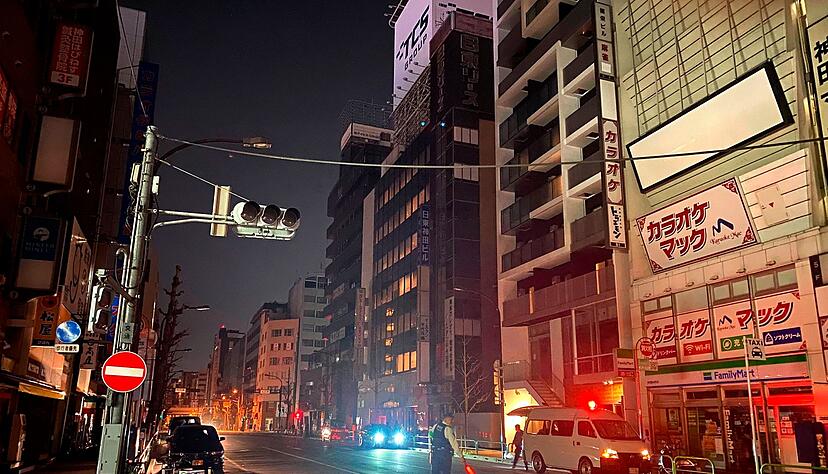 Ein Polizist steht während eines Stromausfalls in Tokio auf der Straße und leitet den Verkehr.