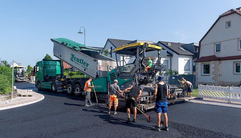 Ein schweißtreibender Tag für die Bauarbeiter. Bei sommerlicher Hitze sind sie mit dem Einbau des 160 Grad heißen Asphalts in der Horkheimer Straße beschäftigt.