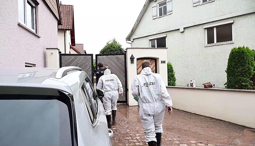 Polizeibeamte der Spurensicherung gehen zu einem Eingangstor eines Grundstücks im Stadtteil Miedelsbach. Sie untersuchen einen Fundort von zwei Leichen, die nach einem Unwetter in einem Keller gefunden worden waren. Polizeibeamte der Spurensicherung gehen zu einem Eingangstor eines Grundstücks im Stadtteil Miedelsbach. Sie untersuchen einen Fundort von zwei Leichen, die nach einem Unwetter in einem Keller gefunden worden waren.