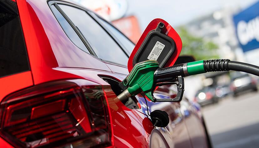 Eine Zapfpistole steckt an einer Tankstelle in einem Auto.