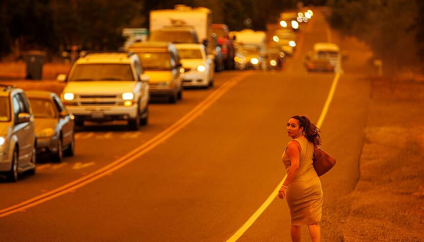 Eine Frau läuft an einer Straße während das Thompson-Feuer brennt Eine Frau läuft an einer Straße während das Thompson-Feuer brennt