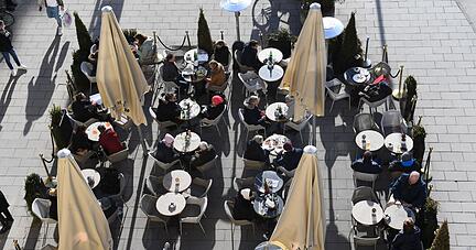 Gäste sitzen vor einem Café in der Sonne. Gäste sitzen vor einem Café in der Sonne.